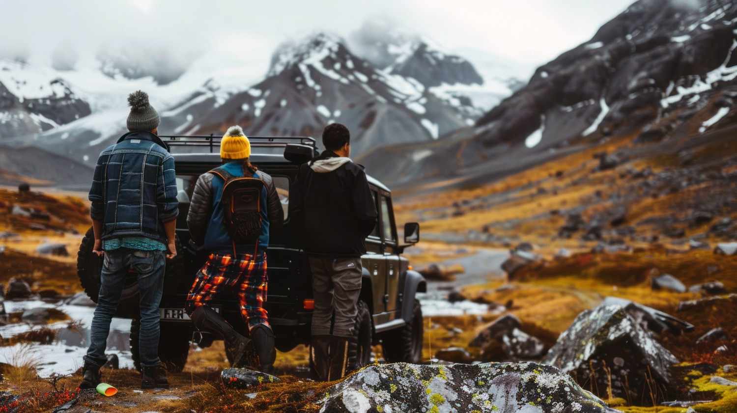 Three travelers standing beside an off-road vehicle and admiring rugged snow-dusted mountains and valleys, capturing the raw adventure vibe of the best treks in India
