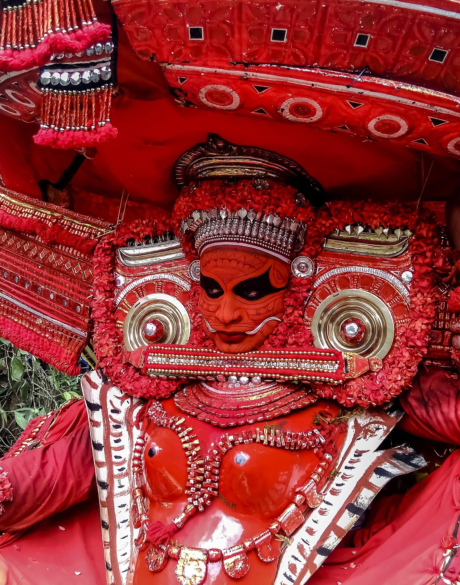 Close-up of a traditional decorated performer in red cultural attire and detailed headgear, showing the spirit of a december festival