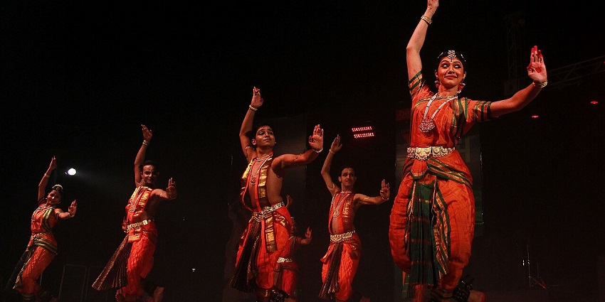 Traditional dancers performing on stage in vibrant attire under warm lights, showcasing the spirit of a December festival.