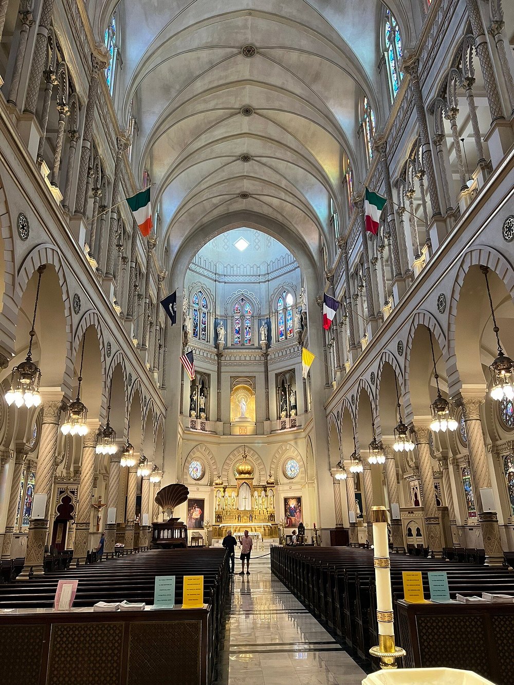 A stunning church interior with high arched ceilings, ornate columns, stained-glass windows, and a golden altar, representing the rich architectural heritage found in many places to visit in Panjim.