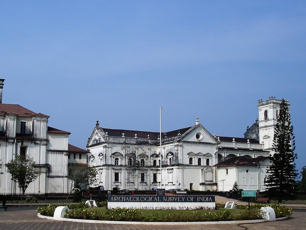 A wide view of a historic white colonial building under the Archaeological Survey of India in Old Goa, surrounded by gardens and walkways, representing the heritage architecture associated with the Goa State Museum.