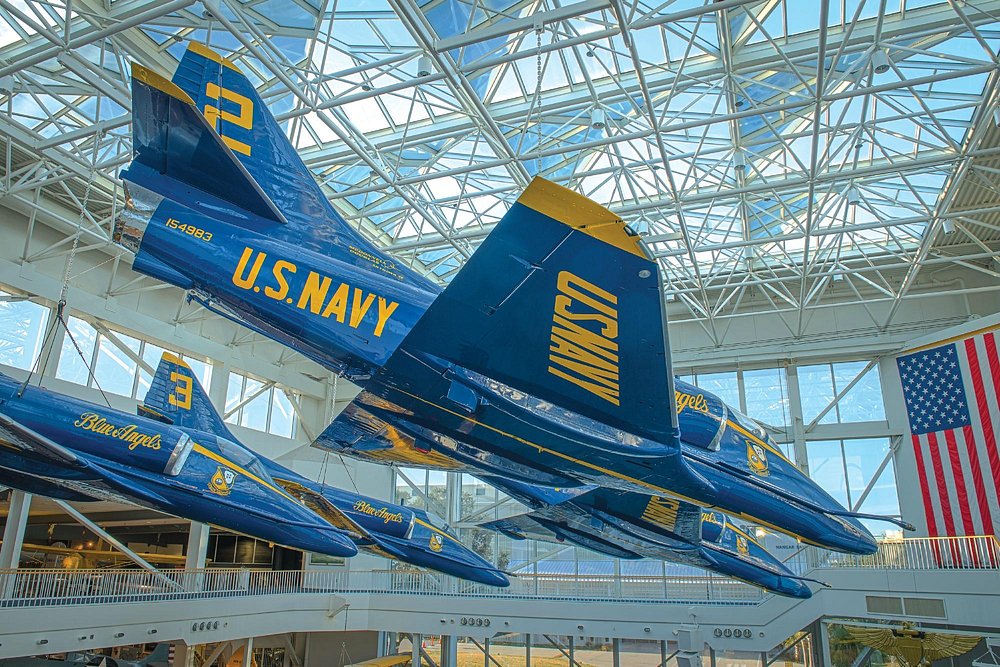 A dramatic indoor display of suspended U.S. Navy Blue Angels aircraft inside a modern aviation museum, creating a grand visual experience similar to what visitors seek when exploring the best museums in Goa.