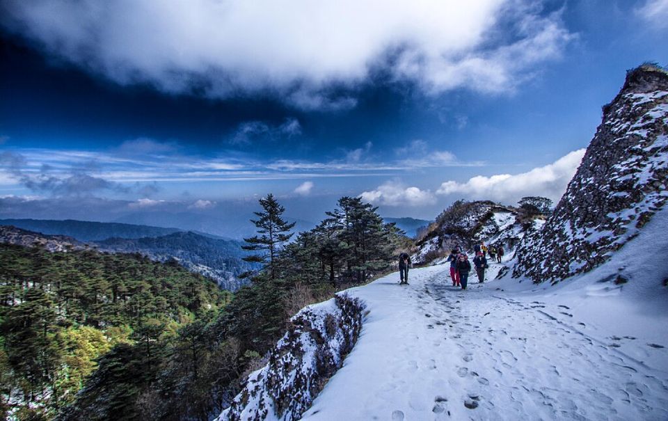 Snow-covered mountain trail leading to the Muktinath Temple entrance gate, with a trekker walking on the path surrounded by winter landscapes—an iconic view often associated with Winter Treks in India.