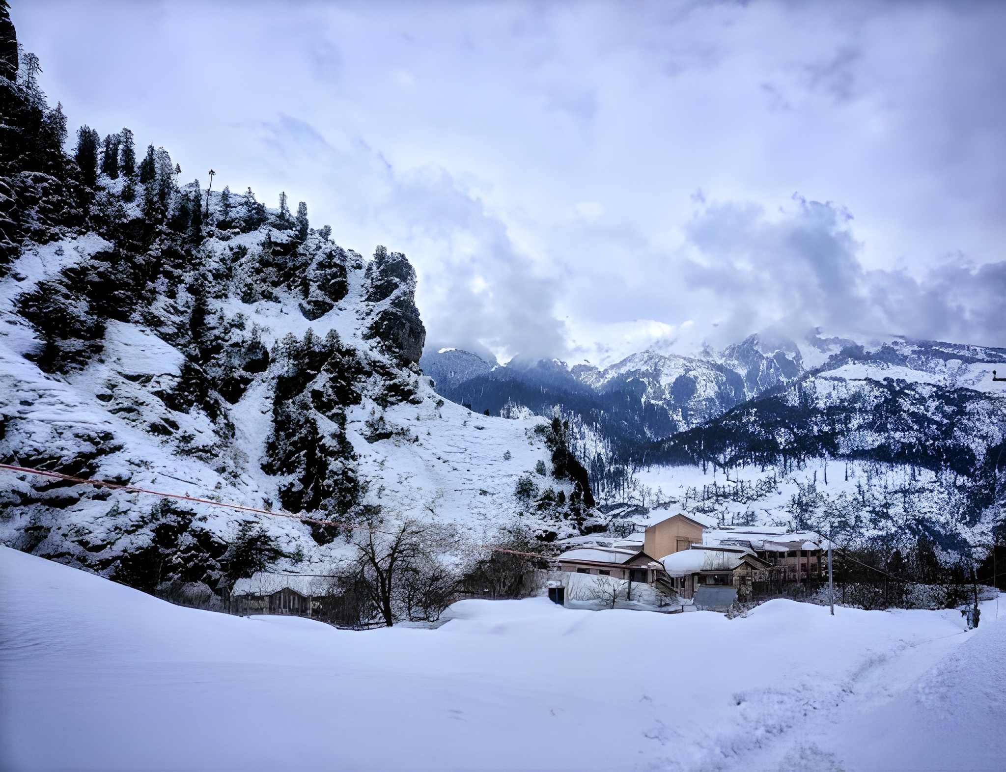 Snow-covered mountains, rocky cliffs, and a quiet village blanketed in white, reflecting the serene beauty of snowfall places in India.