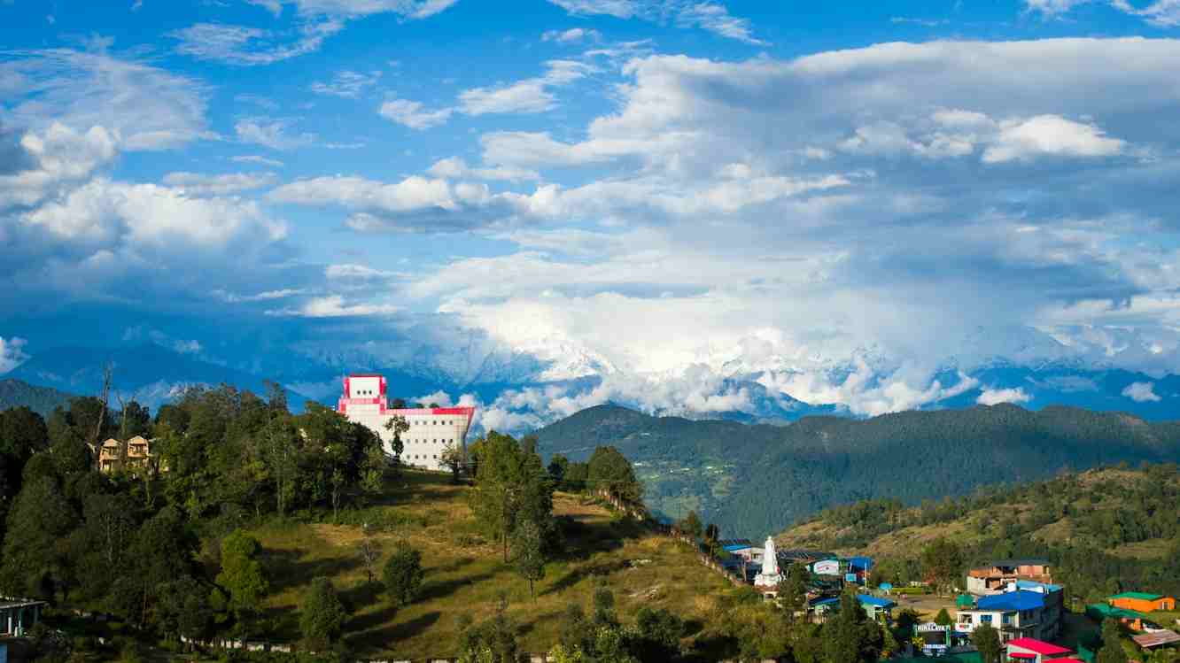 Scenic hill settlement surrounded by clouds during budget winter travel in Uttarakhand Towno
