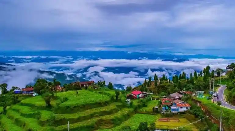 Panoramic view of Darjeeling hills with lush green landscapes, colorful houses, and clouds floating over the valley, one of the top places to visit in India in April – Towno